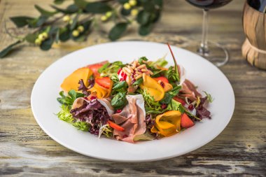 Ahşap masa üzerinde beyaz tabakta sebze salatası jambon ile hizmet