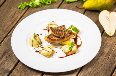 Izgara et ve ahşap masa üzerinde beyaz tabakta armut ile incelik çanak