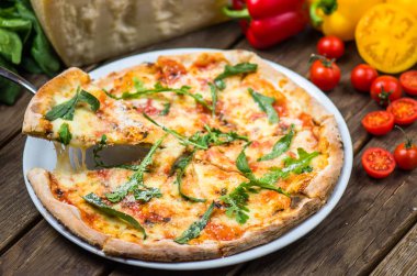 parmesan peyniri, roka ve domates ile güzel pişmiş pizza ahşap masa üzerinde görmek