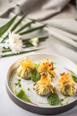 Tepside zemin üzerine çiçekli ıspanak ve sos ile servis hamur tatlısı