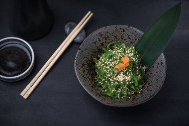 Yosun koyu arka plan üzerinde siyah kase meze Japon salatası