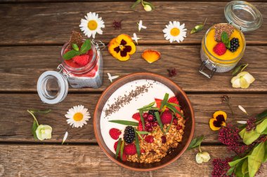 Kahvaltı yoğurt, granola ve çilek kase ve kavanoz chia tatlı çiçekler ahşap tablo