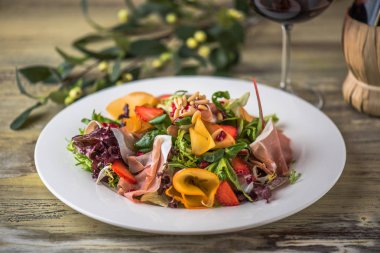 Ahşap masa üzerinde beyaz tabakta sebze salatası jambon ile hizmet