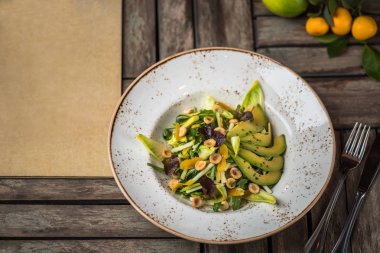 Taze salata avokado ve plaka üzerinde ahşap masa içinde fındık