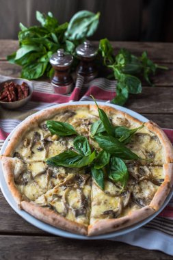 Mantarlı pizza ve ahşap masada fesleğen.