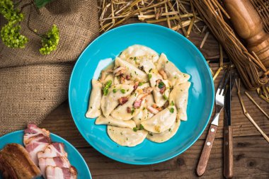 Ahşap masa üzerinde mavi plaka üzerinde Kurutulmuş domuz pastırması ile servis haşlanmış Mantı