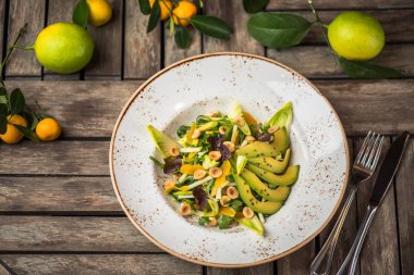 Taze salata avokado ve plaka üzerinde ahşap masa içinde fındık