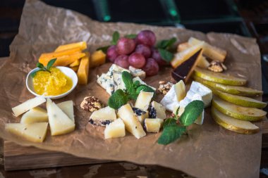Parşömen üzerine peynir ve meyve meze eşliğinde