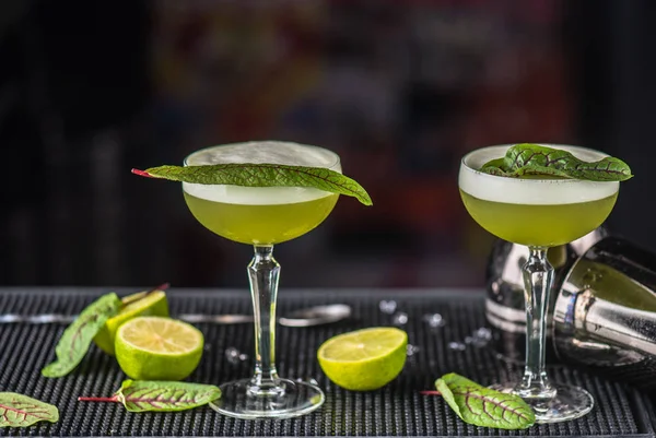 Alcohol sour green cocktail served in glasses on bar counter