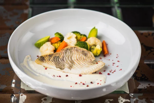 Steamed fish and vegetables on white plate