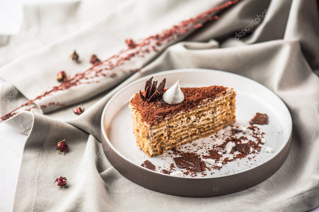 Piece of creamy cake served on plate on tablecloth