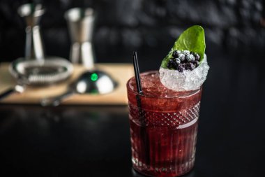 Yaprak ve koyu arka plan üzerinde yaban mersini taze kokteyl cam süslenmiş