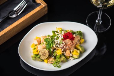 İncelik sebze salatası kadeh beyaz şarap ile siyah arka plan üzerine tabakta servis