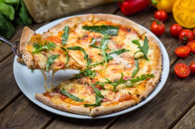 parmesan peyniri, roka ve domates ile güzel pişmiş pizza ahşap masa üzerinde görmek