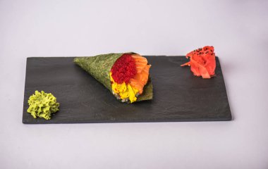 lezzetli suşi koni havyar, avokado, wasabi ve zencefil ile gri arka plan üzerinde kayrak gemide görmek
