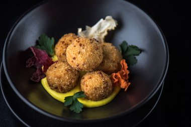 Derin kızarmış peynir topu yığılmış siyah kase sos ile servis