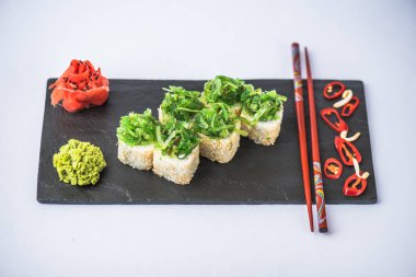 Kayrak beyaz zemin üzerine alınarak deniz yosunu ile süslenmiş Japon suşi roll