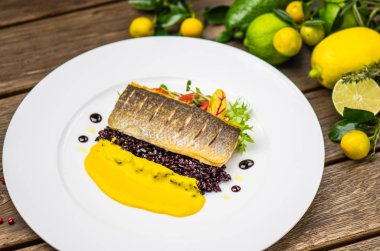 Yatakta Sebze soslu ahşap masa üzerinde beyaz tabakta servis kavrulmuş balık