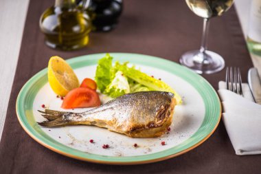 Taze sebze ve cam beyaz şarap ile plaka üzerinde kavrulmuş balık