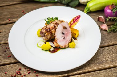 Beyaz ahşap masa üzerinde sebzeli tabakta kavrulmuş domuz eti