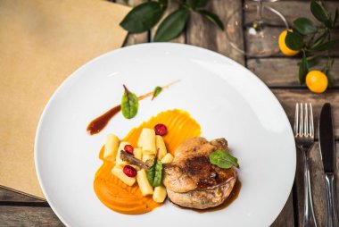 Ahşap masa üzerinde beyaz tabakta ördek bacak garnitür ile servis