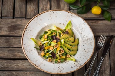 Taze salata avokado ve plaka üzerinde ahşap masa içinde fındık