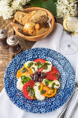 Kırmızı ve sarı domates ve mozzarella peyniri ile taze meze desenli mavi tabakta