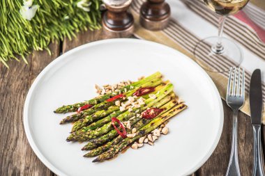 Biber ve beyaz tabakta fındık ile ızgara yeşil kuşkonmaz