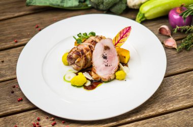 Beyaz ahşap masa üzerinde sebzeli tabakta kavrulmuş domuz eti