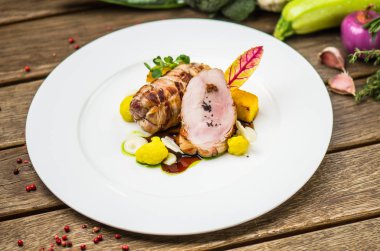 Beyaz ahşap masa üzerinde sebzeli tabakta kavrulmuş domuz eti