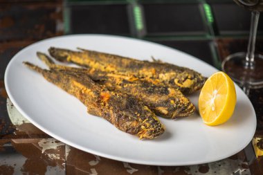 kızarmış balıkla limon kahverengi yüzeyi beyaz plaka üzerinde