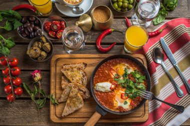 shakshuka, zeytin, biber, domates, ekmek, meyve suyu ve kahve rustik ahşap tablo ile kahvaltı