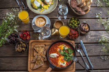 shakshuka, zeytin, biber, domates, ekmek, meyve suyu ve kahve rustik ahşap tablo ile kahvaltı