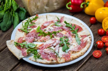 Roka ve ham ahşap masa üzerinde plaka üzerinde İtalyan pizza