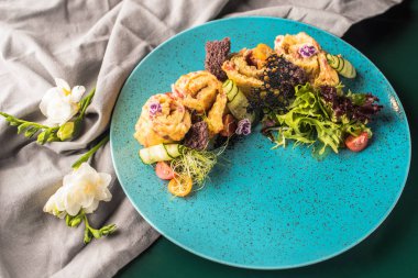 çiçeklerle mavi tabakta sebzeli krep haddelenmiş