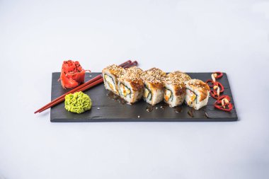 gri arka plan üzerinde kayrak gemide görmek gurme suşi rulo yılan balığı, yemek çubukları, zencefil ve wasabi ile 