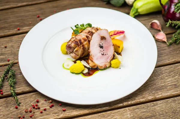 Beyaz ahşap masa üzerinde sebzeli tabakta kavrulmuş domuz eti