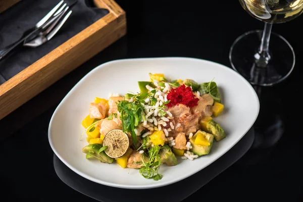 İncelik sebze salatası kadeh beyaz şarap ile siyah arka plan üzerine tabakta servis