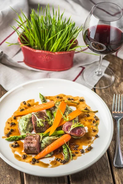 Havuç ile sığır eti ve ahşap masa üzerinde sunulan beyaz tabakta sos