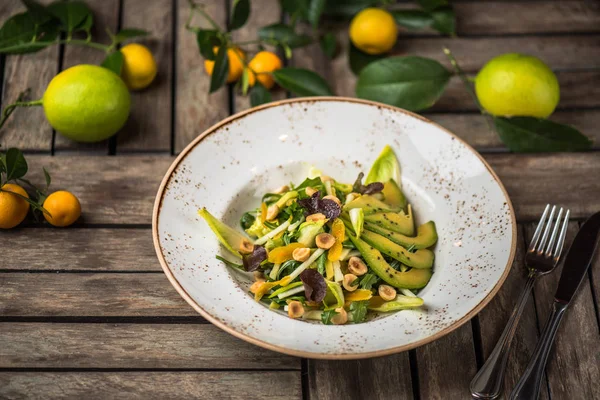 Taze salata avokado ve plaka üzerinde ahşap masa içinde fındık