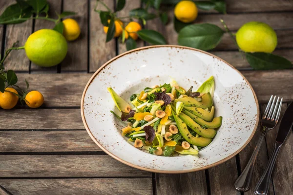 Taze salata avokado ve plaka üzerinde ahşap masa içinde fındık