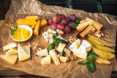 Parşömen üzerine peynir ve meyve meze eşliğinde