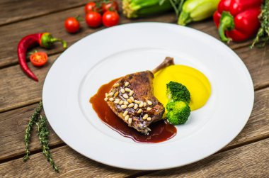 Taze sebze ile ahşap masa üzerinde beyaz tabakta ördek bacak sos ve sebze püresi ile servis