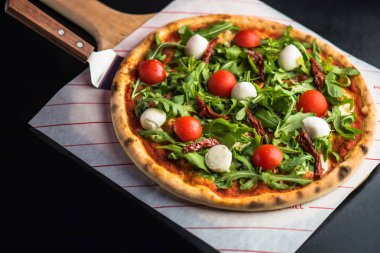 Pizza taze domates, roka ve mozzarella peyniri koyu arka plan üzerinde ahşap tahta üzerinde