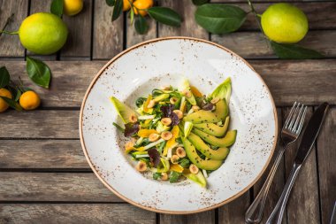 Taze salata avokado ve plaka üzerinde ahşap masa içinde fındık
