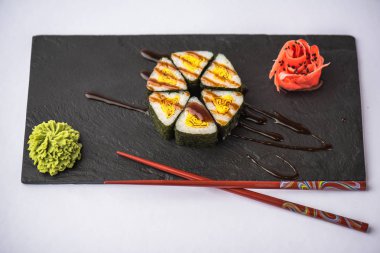 zencefil, wasabi, soya sosu ve gri arka plan üzerinde kayrak gemide yemek çubukları ile lezzetli üçgen suşi