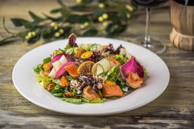 Ahşap masa üzerinde beyaz plaka üzerinde kızarmış tavuk ile sebze salatası