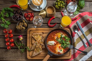 shakshuka, zeytin, biber, domates, ekmek, meyve suyu ve kahve rustik ahşap tablo ile kahvaltı