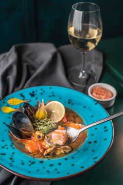 Deniz ürünleri tabak bardak beyaz şarap ile siyah kumaş üzerine mavi tabak içinde