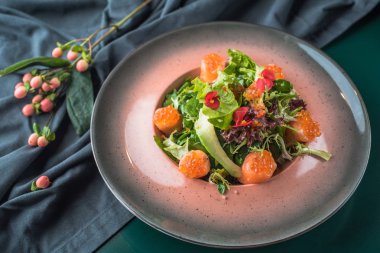 Deniz ürünleri meze taze yeşillikleri ile koyu kumaş tabakta servis 